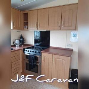 uma cozinha com armários de madeira e um forno com placa de fogão em J & F caravan em Skegness