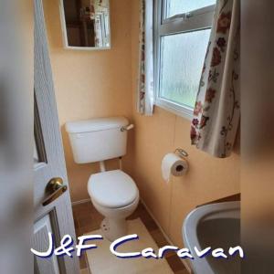 ein kleines Bad mit einem WC und einem Fenster in der Unterkunft J & F caravan in Skegness