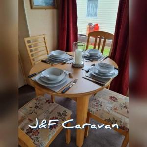 einem Holztisch mit Tellern und Utensilien darauf in der Unterkunft J & F caravan in Skegness