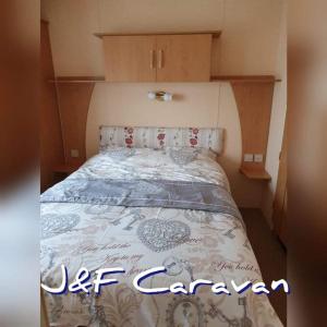 Bett in einem kleinen Zimmer mit Bettüberwachung in der Unterkunft J & F caravan in Skegness