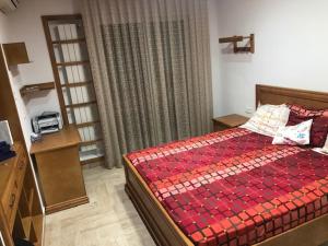 a bedroom with a bed with a red comforter at Alcasar Beach 3 rooms apartment in Sousse