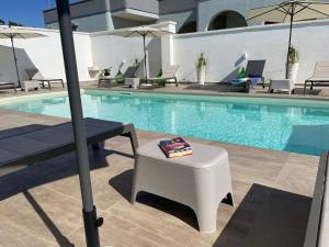 托雷蘇達的住宿－Elite Luxury Residence，一个带桌子、长凳和遮阳伞的游泳池