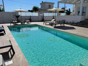 a swimming pool with chairs and umbrellas on a building at Elite Luxury Residence in Torre Suda