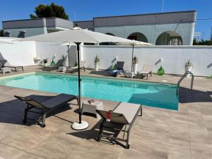 una piscina con tavolo, ombrellone e sedie di Elite Luxury Residence a Torre Suda
