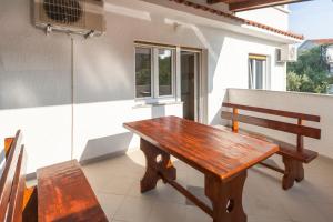 a wooden table and a bench on a balcony at Apartments & Rooms Strčić Krk in Krk