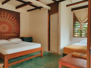 a bedroom with two beds and a table and a window at Hostal El Bohío in Palomino