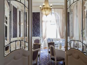Hotel Royal St Georges Interlaken MGallery Collection في إنترلاكن: غرفة طعام مع طاولة وكراسي وثريا