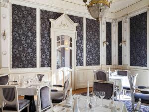 Hotel Royal St Georges Interlaken MGallery Collection في إنترلاكن: غرفة طعام بها طاولات وكراسي وثريا