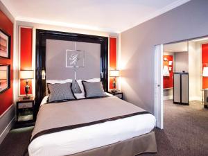 a bedroom with a large bed with red walls at Park Hôtel Grenoble - MGallery in Grenoble