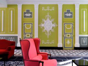 a living room with two chairs and green walls at Hôtel & Spa Jules César Arles - MGallery Hotel Collection in Arles
