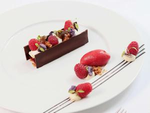 トゥールーズにあるLa Cour des Consuls Hotel and Spa Toulouse - MGalleryのチョコレートケーキ二枚とイチゴの皿