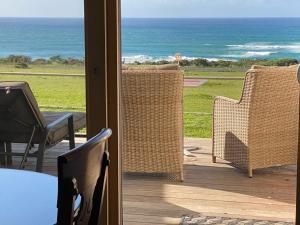 a patio with wicker chairs and a view of the ocean at Seacroft Estate in Apollo Bay