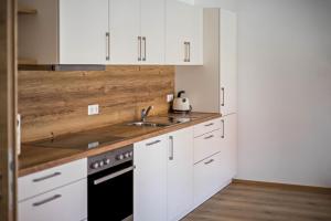 a kitchen with white cabinets and a sink at Ferienwohnung Häfele 2 in Bad Wurzach +13 photos