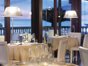 a dining room with tables with white chairs and lamps at GH Palazzo Suite & SPA in Livorno