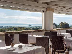 a restaurant with white tables and chairs and a large window at Borgobianco Resort & Spa Polignano - MGallery Collection in Polignano a Mare