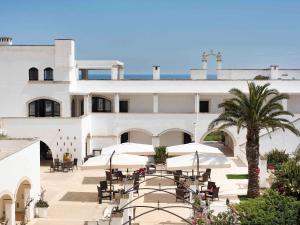 um grande edifício branco com mesas e guarda-sóis em Borgobianco Resort & Spa – MGallery Hotel Collection em Polignano a Mare