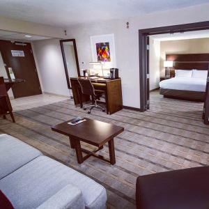a hotel room with a bed and a desk and a living room at Holiday Inn Charlotte Airport by IHG in Charlotte +17 photos