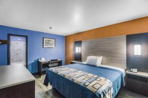 a bedroom with a bed with blue walls and a desk at Scottish Inns in Carrollton