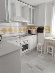 a white kitchen with white cabinets and a microwave at Apartamento Nao Victoria in Sanlúcar de Barrameda