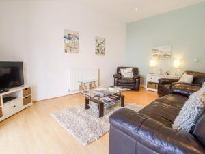 a living room with a couch and a table and a tv at Maritime Mews, 6 The Oakleys in Porthmadog