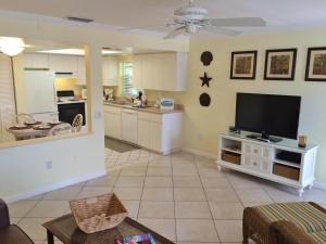 a living room with a flat screen tv and a kitchen at Siesta Palms By the Beach in Sarasota