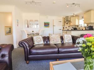 a living room with a leather couch and a kitchen at Sea View apartment in Porthmadog