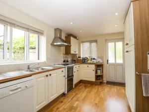 een keuken met witte kasten en een houten vloer bij Belview Cottage in Sturminster Newton