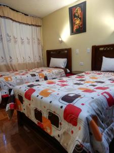 a bedroom with two beds with a colorful comforter at Hotel Navarra in Riobamba