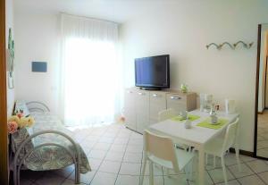 een woonkamer met een witte tafel en een tv bij Green Holiday Flat with pool close to the beach in Bibione