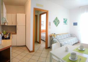 een keuken en een woonkamer met een bank bij Green Holiday Flat with pool close to the beach in Bibione
