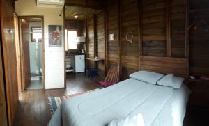 ein Schlafzimmer mit einem Bett in einem Zimmer mit Holzwänden in der Unterkunft Cabana aconchegante Praia do Rosa Rosamarina in Imbituba