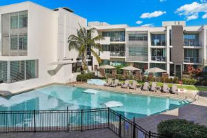 a swimming pool in front of a building at Element on Coolum Beachfront Sunshine Coast in Coolum Beach