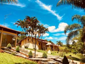 a house with palm trees in front of it at Hotel Fazenda Colina in Ouro Fino