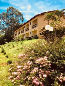a building on a hill with flowers in front of it at Hotel Fazenda Colina in Ouro Fino