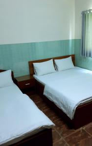 two beds in a room with white sheets at Que Huong Coconut Hotel in Giồng Tú Ðiền