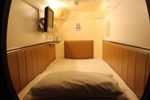 a small room with a bed and a television at Capsule and Sauna New Japan EX (Male Only) in Hiroshima