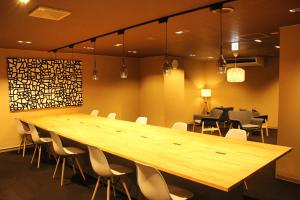 a large wooden table in a room with chairs at Capsule and Sauna New Japan EX (Male Only) in Hiroshima