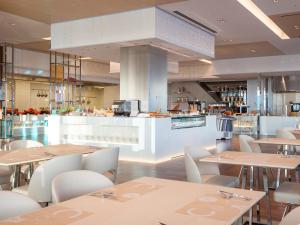 a restaurant with tables and chairs and a kitchen at Osaka Marriott Miyako Hotel in Osaka