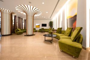 a living room with green couches and a table at Horizon Hotel in Al Başrah