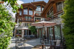 a house with a balcony and a patio with umbrellas at Alpenlodge in Zermatt