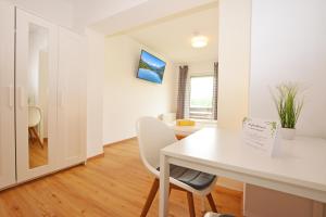 a white dining room with a white table and chairs at Sonniges Apartment mit Balkon in Ruhelage in Villach