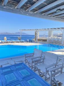 uma piscina com cadeiras e o oceano ao fundo em Blue Harmony Suites of Mykonos em Míconos