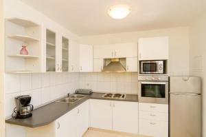 a white kitchen with white cabinets and appliances at Apartments Plavac Mali in Potomje