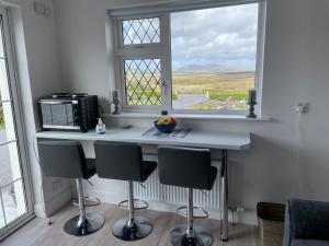 a kitchen with a counter with chairs and a window at Stay Skelligs in Portmagee