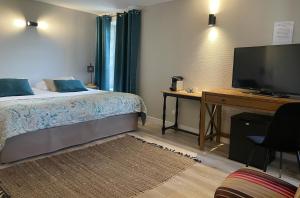 a bedroom with a bed and a desk with a television at Logis Hôtel Le Moulin de Chalons in Le Gua