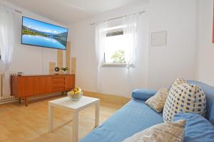 a living room with a blue couch and a tv at Ferienwohnung Alpenblick in Villach