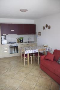 cocina y sala de estar con sofá rojo y mesa en La Terrazza sul Lago, en Malcesine