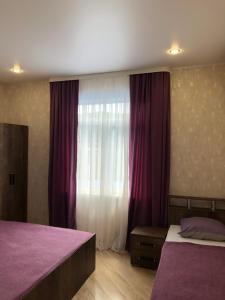 ロオにあるGuest house U Arturaのベッドルーム1室(ベッド2台付)、紫色のカーテン付きの窓が備わります。
