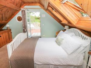 a bedroom with a white bed in a attic at The Barn in Dalbeattie