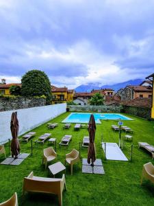 una piscina con tumbonas y una zona de césped con sillas y mesas. en Hotel Lauro, en Gravedona